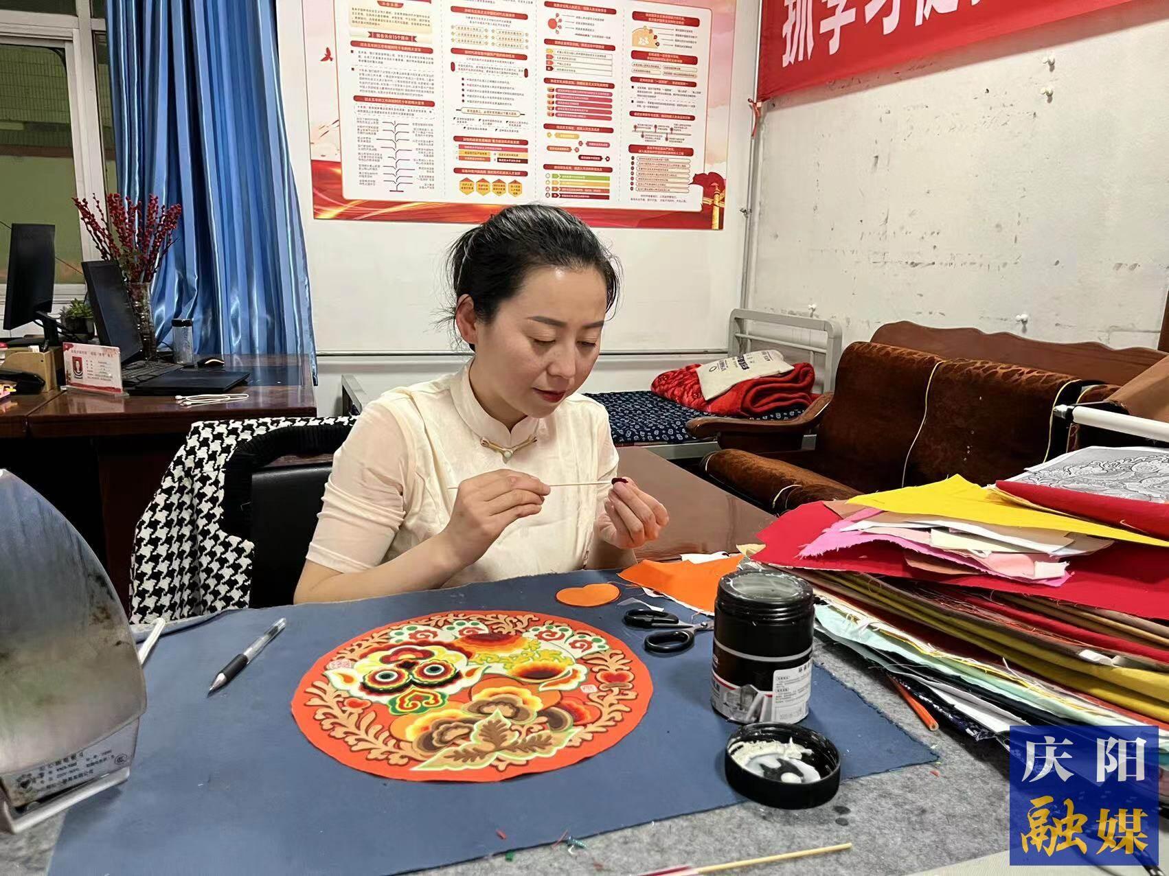 李慶英正在創(chuàng)作布貼畫(huà)作品。